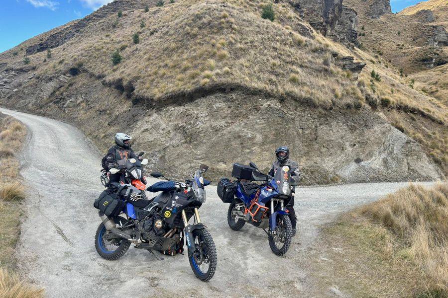 Two riders on a High Country gravel switchback among tussock and schist