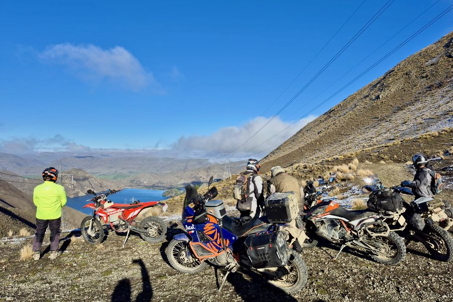 Riders stopped on a tussock ridge looking down over a Waitaki lake