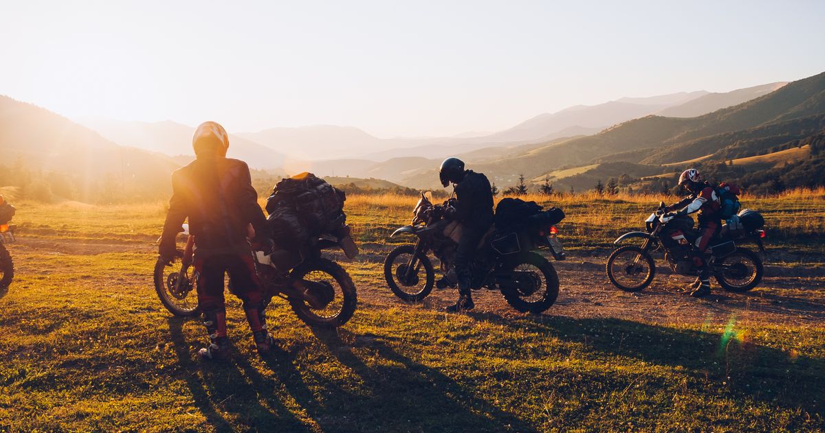 A group of adventure riders stopped together in the hills at golden hour